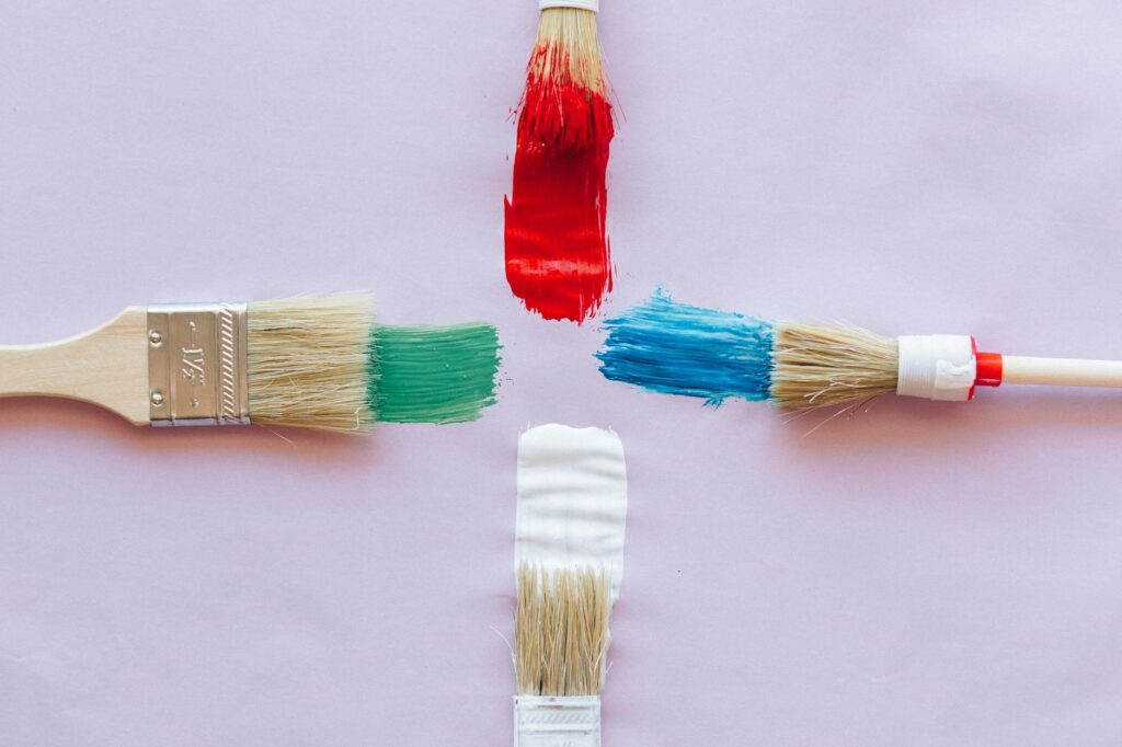 Round natural-bristle paint brush loaded with chalk paint next to a painted dresser